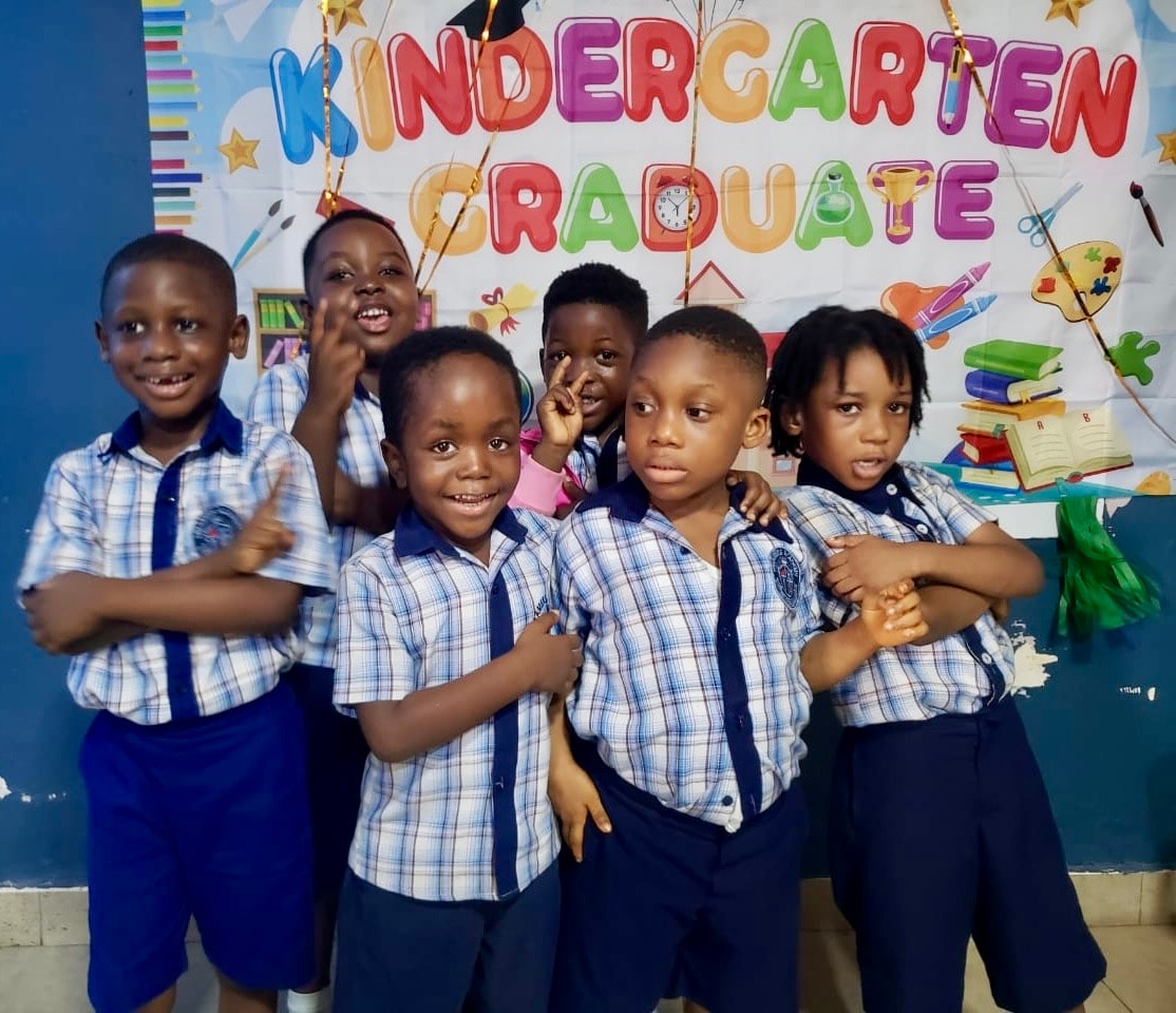 Kindergarten graduates posing in front of the graduation banner