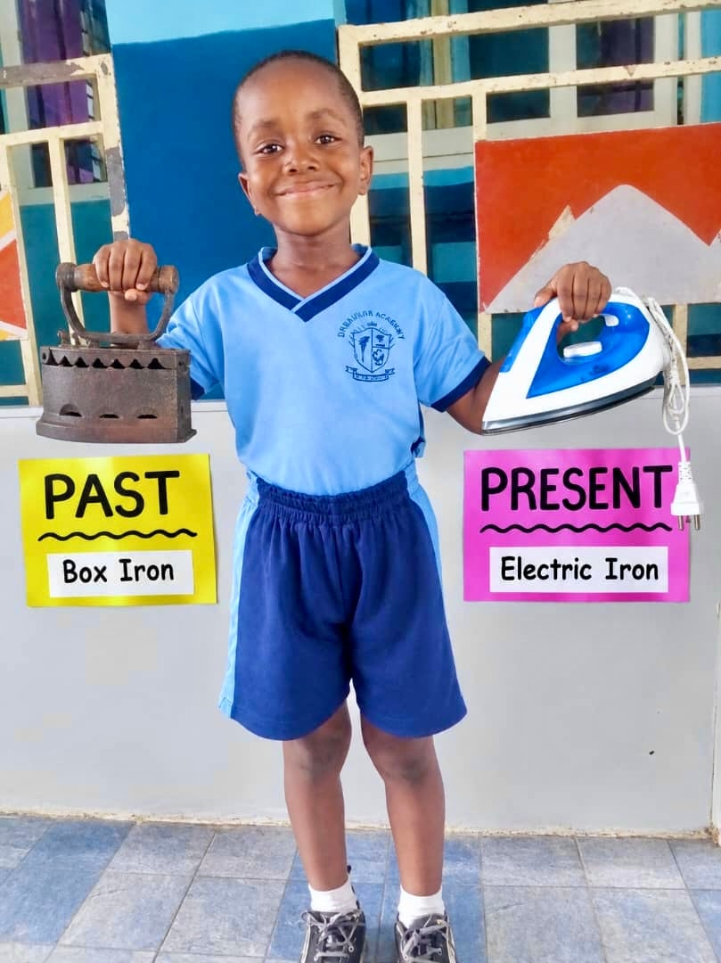 Student holding a box iron (past) and electric iron (present)