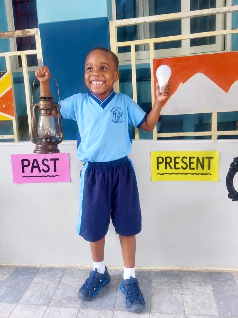 Student holding a lantern (past) and light bulb (present)