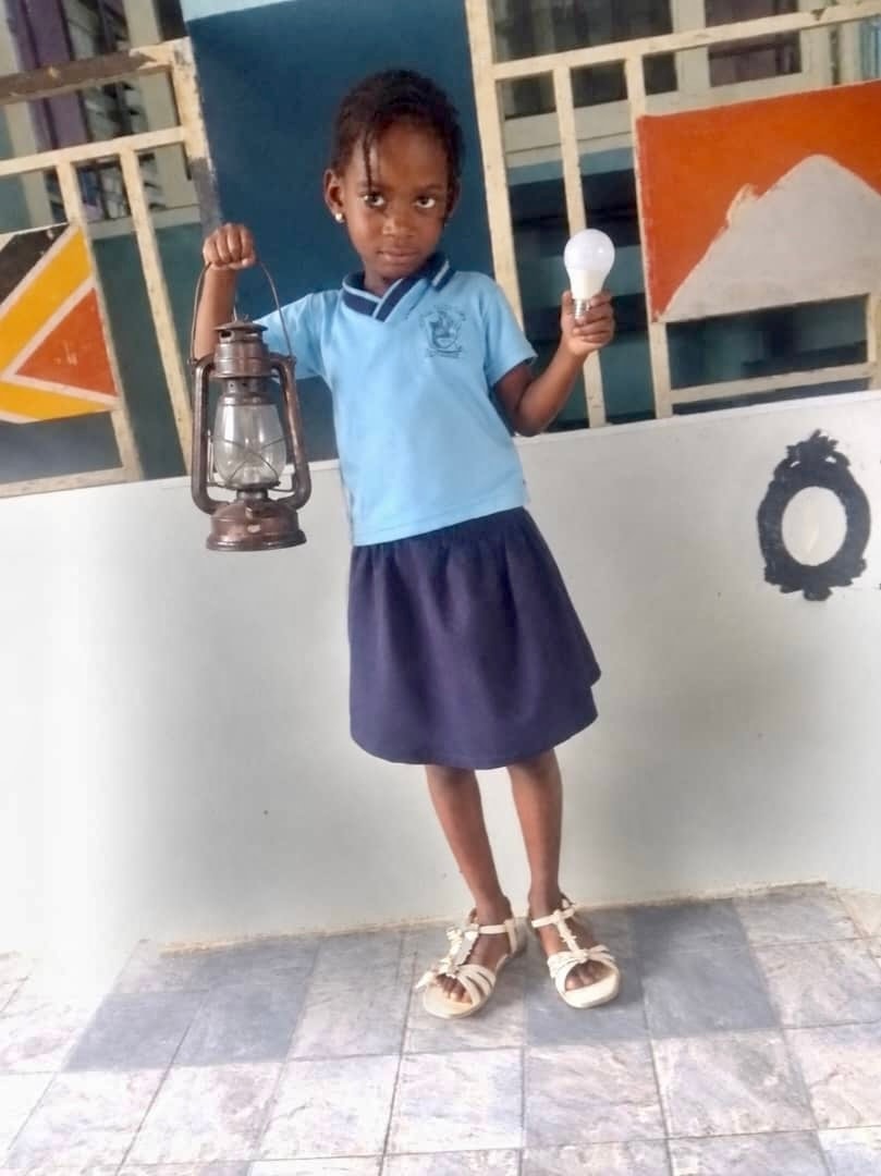 Student holding a lantern (past) and light bulb (present)