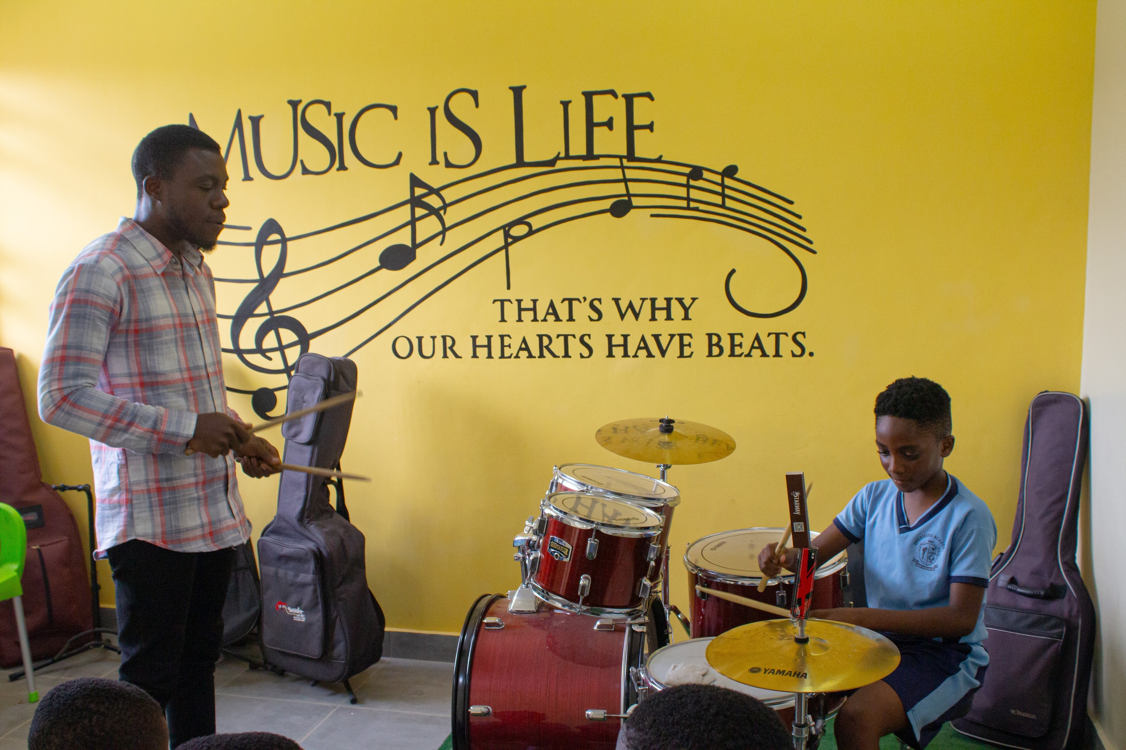 Music teacher instructing a student on drums at Dreamers Academy-GH